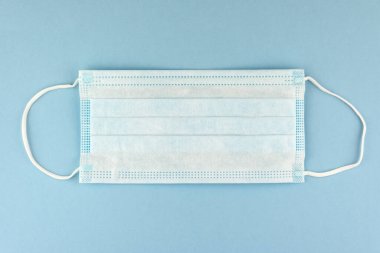 Soluk mavi arka planda Coronavirus gibi virüslere karşı cerrahi koruma maskesi