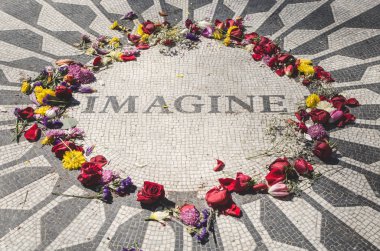 John Lennon 'ın Central Park, New York' taki anıtının manzarası hayranlar ve turistler tarafından bırakılan renkli çiçeklerle çevrili. Hayal et, üzerinde okunabilir..