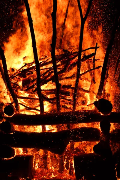 Изумительный огненный костер в деревне в темную ночь. Горение дров создает большое пламя, вспышки, дым, газ и генерирует широкий свет вокруг огня. Вертикальное фото . — стоковое фото
