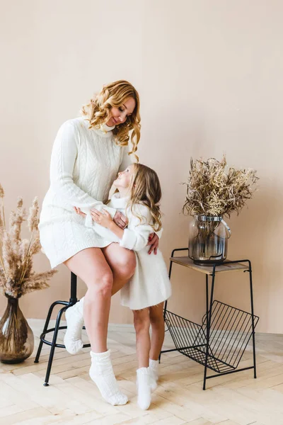 Maman et fille sur fond beige en pull blanc — Photo