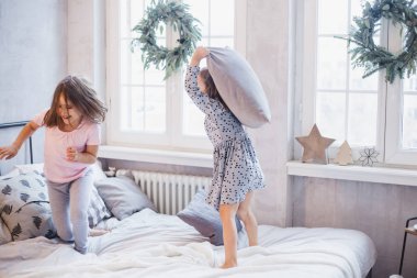İki kız, yatakta kavga eden kız kardeşler, Noel çelengi ile süslenmiş pencere, hayat, çocukluk