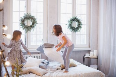 İki kız, yatakta kavga eden kız kardeşler, Noel çelengi ile süslenmiş pencere, hayat, çocukluk