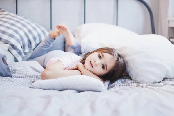 Ragazza sdraiata sul letto, bambina che riposa tra cuscini e coperte, sogni — Foto Stock