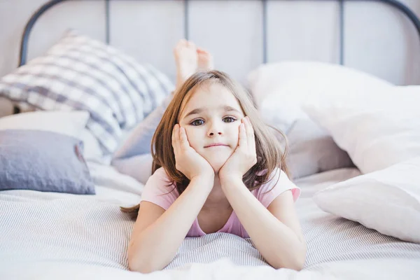 Girl lying on the bed, little girl resting among the pillows and blankets, dreams — Stock Photo, Image