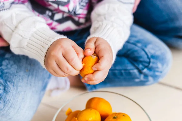 Meisje reinigt mandarijnen, mandarijnen in handen — Stockfoto