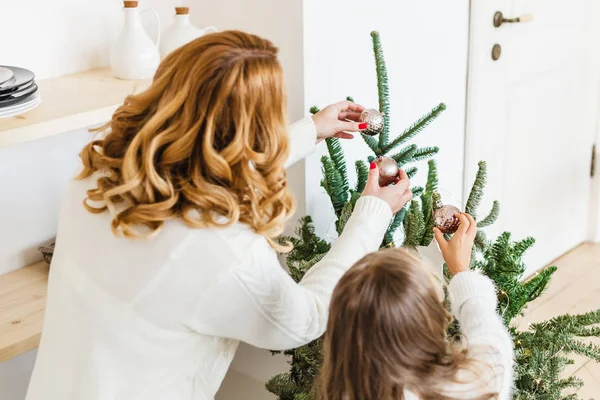 Uma menina com sua mãe perto da árvore de Natal, o interior decorado para o ano novo e Natal, família e alegria, tradições — Fotografia de Stock