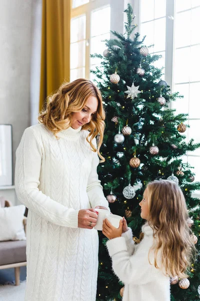 Une fille avec sa mère près du sapin de Noël, l'intérieur décoré pour la nouvelle année et Noël, famille et joie, traditions — Photo