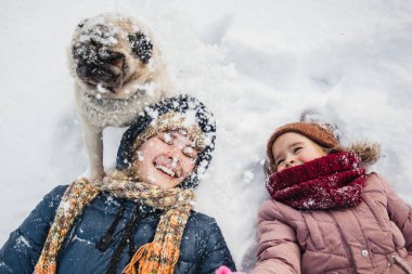 Anne ve kızı karda yatıyorlar, köpekle, karla ve oyunlarla konuşuyorlar.