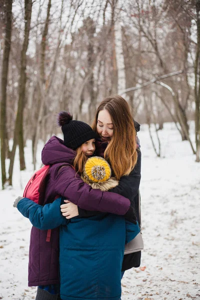 Мати обіймає своїх дітей, дочку і сина, сестру і брата, родину, ходячи в зимовому лісі. — стокове фото
