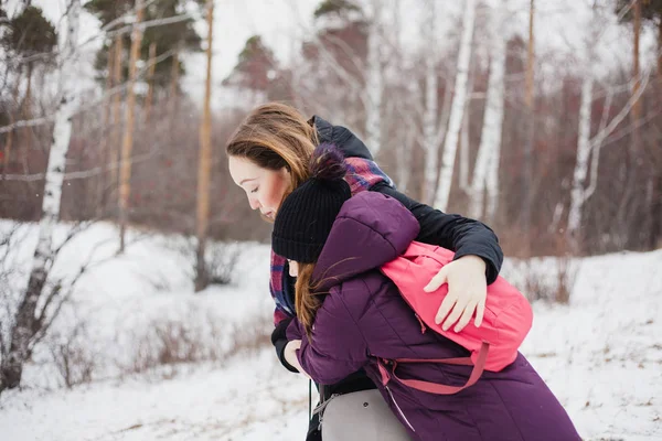 Mom hugs her daughter on a winter walk, warm clothes — 스톡 사진