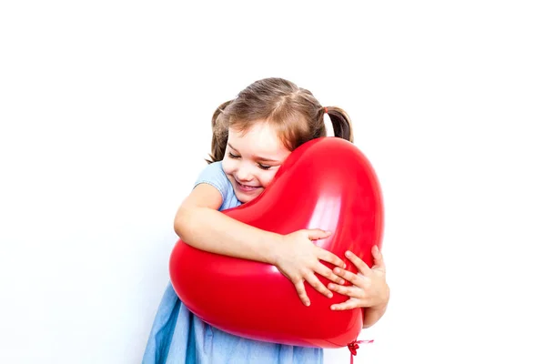 Little girl holding a beautiful red heart-shaped balloon for a gift for Valentine's day, lovers, Valentine's day, family and heart — Stock Photo, Image