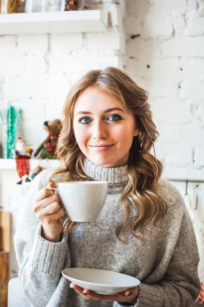 European-looking girl sitting in the kitchen, drinking tea or co — 스톡 사진