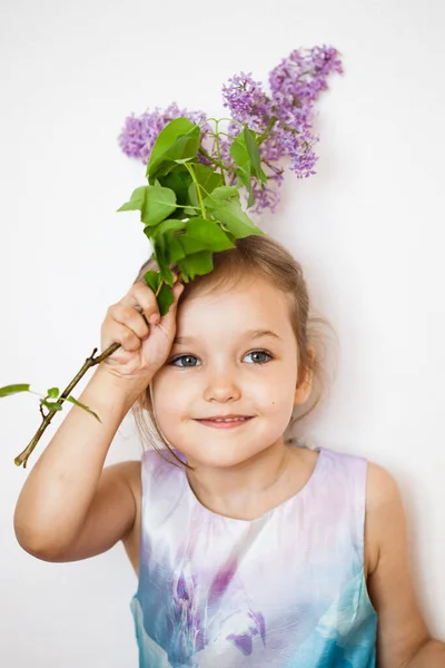 Uma menina em um fundo branco fica e mantém ramos de lilás, kurst florescendo, lilás, primavera e verão — Fotografia de Stock