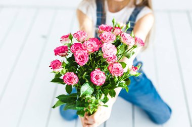 Avrupa görünümlü uzun sarı saçlı, gülümseyen, duyguları, neşesi, dostluğu, ailesi, elinde güller, narin çiçekler, annesi için çiçekler olan bir kız.