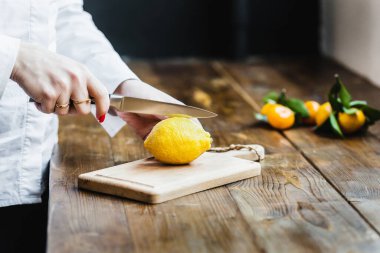 Limon ve limon dilimlemek için pansiyon, yemek, salata ve aperatifler için hazırlanma, limon suyu, dekorasyon tabakları, aşçı, limon kesme, elinde bir mutfak bıçağı, limon kesme