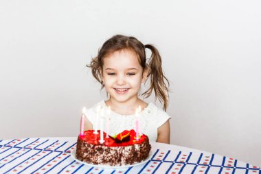 Küçük kız ve doğum günü pastası, mumları üfler, dilek tutar, pasta ve mumlar, doğum günü hediyeleri, aile, anne ve baba