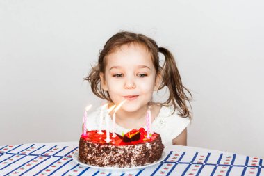 Küçük kız ve doğum günü pastası, mumları üfler, dilek tutar, pasta ve mumlar, doğum günü hediyeleri, aile, anne ve baba