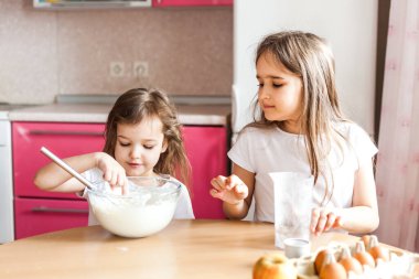 Kardeşler kahvaltı hazırlar, hamur işleri, un, süt, yumurta, gözleme kasede, çocuklar annelere yardım eder, aile kahvaltısı yapar, yemek yapar.