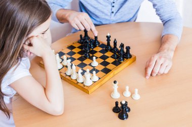 Kız ve baba evde bir oyun oynuyor, satranç, beyin gelişimi için bulmaca, zihinsel zeka, çocuk gelişimi, okul, ev, karantina, tatil, aile ile zaman geçirme