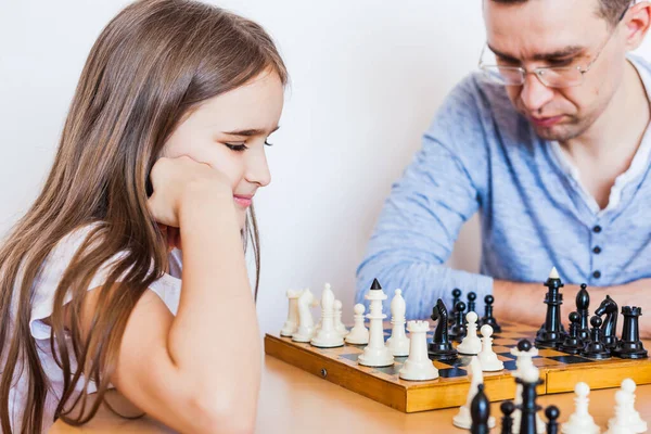 Girl and dad play a game at home, chess, puzzle for brain development, mental intelligence, child development, school, home, quarantine, vacation, time with family