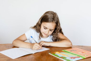 A school girl does homework at home, classes via the Internet, online, learning a foreign language, learning English, notebook, learn letters and words clipart