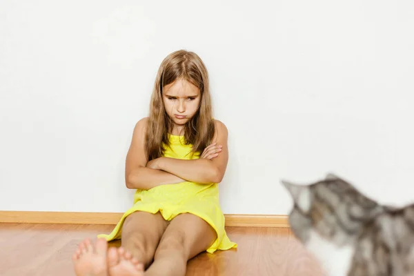 Girl sitting on the floor, upset, offended by the cat, pet, scratched, hand, feet, yellow dress, baby, family, pet care