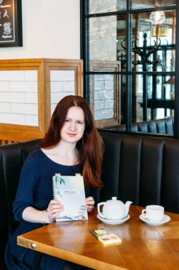 Bir kafede Avrupalı görünümlü bir kız, fincandan çay ya da kahve içiyor, sohbet, toplantı, öğle yemeği, arkadaşını bekliyor.