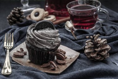 Koyu mavi kumaşlı bir fincan meyveli çayla Orio keki..