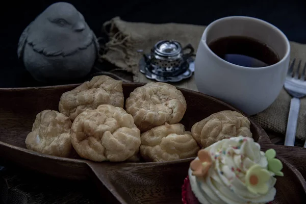 Пора завтракать. Шу сливки с кексом и чай на деревянной спине — стоковое фото