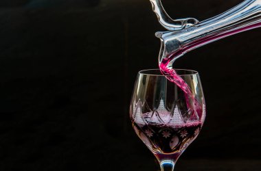 Sürahiden sürahiye kırmızı şarap döken düz bir kompozisyon.
