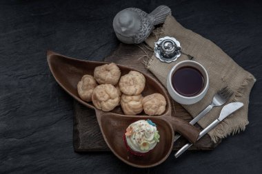 Kahvaltı vakti geldi. Choux kremalı kek ve tahta sırtlı çay.