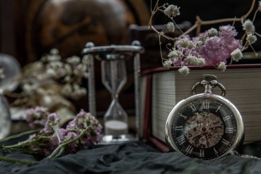 Cep saati, bulanık eski kitap yığını, kum saati, klasik dürbün ve karanlık arka planda dünya masası küresi. Seyahat ve Öğrenme Konsepti, Klasik Biçim.