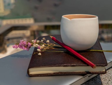 İşyeri, dizüstü bilgisayarı, meyve suyu çiçeği ve kalem konforlu ofis masası ve bulanık şehir manzaralı bir defter. Seçici odak.