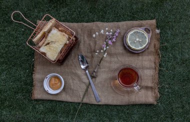 Öğle yemeği - Çay ve Limon, yeşil çimenlikte gevrek sarımsaklı tost ile servis edilir. Üst Görünüm, Seçici Odaklanma.