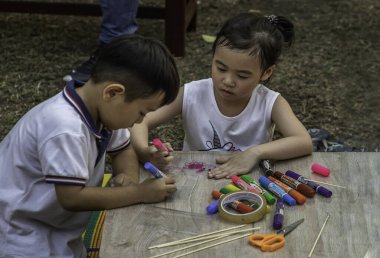 Bangkok, Tayland - 22 Aralık 2019: parkta beyaz kalemle çizim yapan küçük kız ve oğlan.