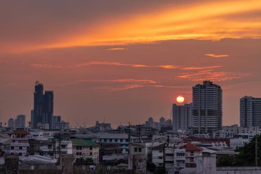 Bangkok, Tayland - 11 Nisan 2020: Günbatımında batan güneşli siluetli şehirlerin ışığında Bangkok City gökdelenleri. Ofis binasının üzerinde güzel bir gün batımı. Seçici odak.