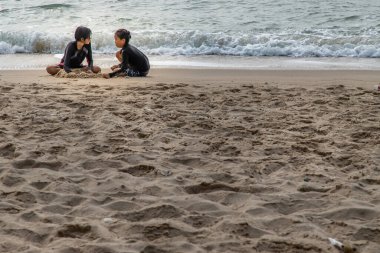 Phetchaburi, Tayland - 15 Mart 2020: Güneşli bir günde tropik plajda kum oynayan iki kız. Tatil gezisi. Seçici odak.