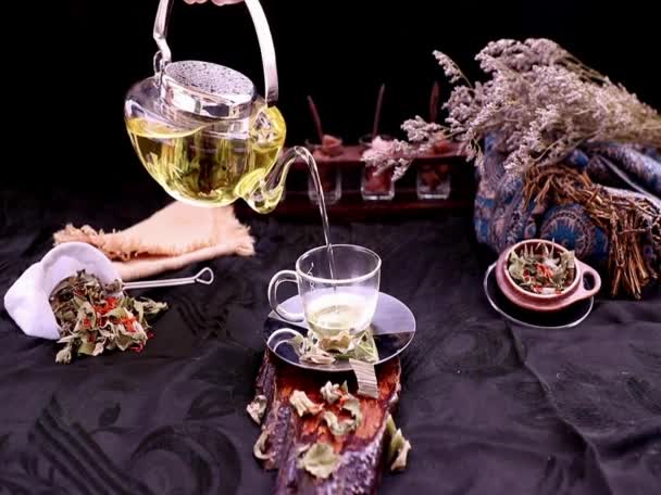 インド産のマルスフラバネ植物の葉を入れたホットパンダン葉茶とグラスティーポットから茶葉と茶葉を入れたグラスにサフラワードライ サフラン代用品 を注ぎます 選択的焦点 — ストック動画