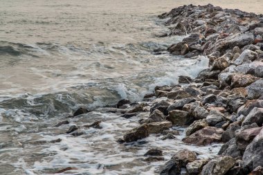 Kayalar ve deniz: Sabahleyin sakin sahilde kayalara vuran deniz dalgalarının görüntüsü. Tam olarak odaklanamıyorum..