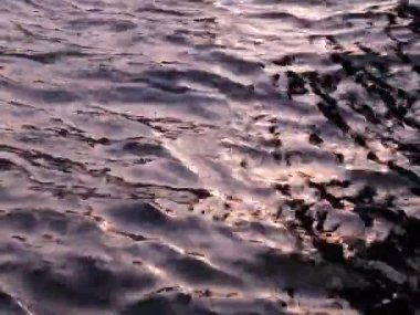 Gün batımında, bulutlu bir günde nehir yüzeyi ve güneş yavaş çekimde parlar. Gökyüzünün doğal soyutlanması suya yansıyor. Dalga dokusu.