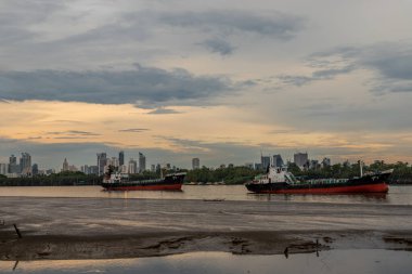 Bangkok, Tayland - 11 Mayıs 2020: İki kargo gemisi akşam gökyüzü arka planında Chao Stevaya nehrinin ortasına park edildi.