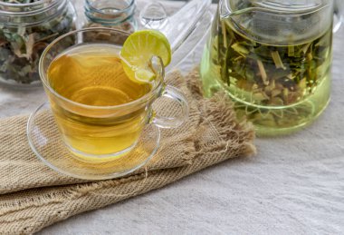 Öğleden sonra beyaz masada kahverengi şekerle servis edilen bir fincan limonlu pandan çayı ile ferahlatıcı ve keyfini çıkarın. Tayland bitkisi ve sağlıklı içecek konsepti. Üst görünüm, Seçici odak, Boşluğu Kopyala.