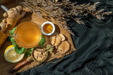 Limon ve nane aromalı sıcak zencefil suyu, kahverengi şeker ve balla servis edilmiş kök ve zencefil dilimleri. Sıcak zencefil suyu vücut ısıtmaya yardımcı olur, sağlıklı içecek..