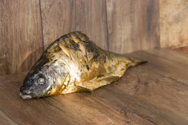 Hot smoked carp on old wooden boards. — Stock Photo, Image