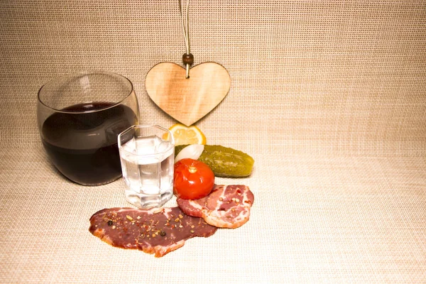 Romantic rustic dinner. Vodka and whiskey with jerky. Canned cucumbers and tomatoes. Home cooking. On a canvas tablecloth.