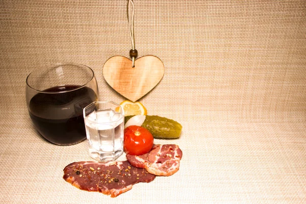Romantic rustic dinner. Vodka and whiskey with jerky. Canned cucumbers and tomatoes. Home cooking. On a canvas tablecloth.