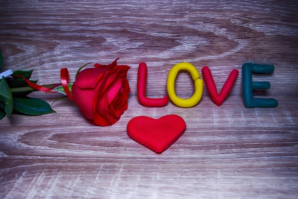 Hermosa rosa, corazón rojo y la palabra amor. Sobre un fondo de madera. Día de San Valentín. Concepto de diseño . —  Fotos de Stock