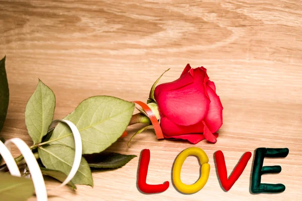Gyönyörű ünnepi rózsa és a szerelem szó. Fából készült háttérrel. Szent Valentin-nap. Tervezési koncepció. — Stock Fotó