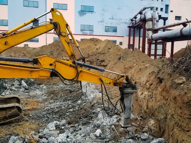 İnşaat işi, sökülüyor. Endüstriyel hidrolik çekiç kullanılarak güçlendirilmiş beton yapıların profesyonel yıkımı. Metal alaşımlı çubuklar. Beton enkazı ve kırıntıları.