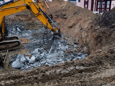 İnşaat işi, sökülüyor. Endüstriyel hidrolik çekiç kullanılarak güçlendirilmiş beton yapıların profesyonel yıkımı. Metal alaşımlı çubuklar. Beton enkazı ve kırıntıları.